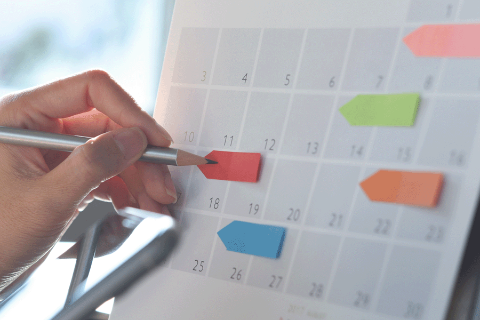 Hand pencilling in dates on a calendar