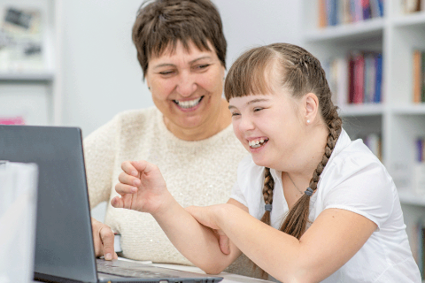 Teacher and student working on a laptop